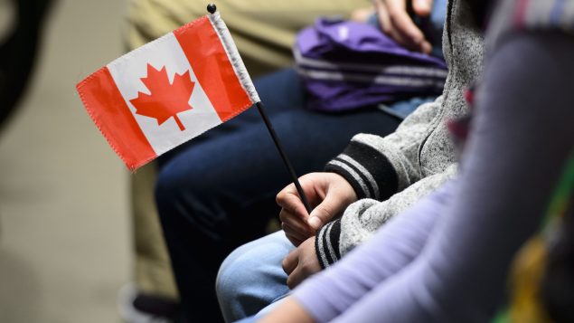 seated person holding a small Canadian flag